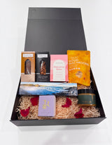 The Wild flower gourmet gift hamper in a black box with cookies, nuts, tea, macaroons, chocolate, and a soy candle.