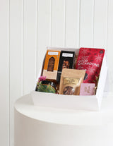 The Wild flower Luxury Treat Box featuring gourmet cookies, macaroons, chocolates, and a candle in a white gift box.
