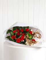 The Wild flower Romeo bouquet featuring premium red roses and metallic gold foliage wrapped in white paper.