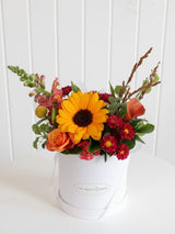 The Wild flower Wild Flower Box featuring a vibrant sunflower, orange rose, and seasonal blooms in a white gift box.