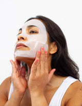A woman applying a translucent Yae Bio Collagen Face Mask from The Wild flower for deep hydration and skin firming.