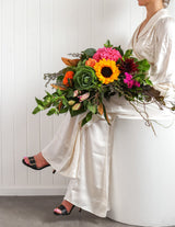 The Wild flower Florist Surprise bouquet featuring bright sunflowers, pink hydrangeas, and greenery held by a model.