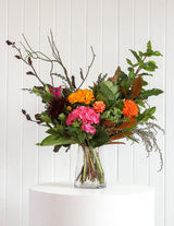 The Wild flower Florist Surprise bouquet featuring bright seasonal flowers like pink hydrangea and orange dahlias in a vase