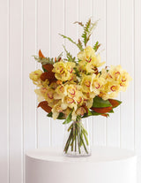 The Wild flower Cymbidium Orchid stem bouquet with yellow flowers and seasonal foliage in a glass vase