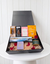 The Wild flower gourmet artisan gift hamper in a black box with cookies, nuts, macaroons, tea, and a soy candle.