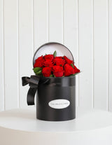 The Wild flower Juliet arrangement featuring a dozen premium red roses in a signature black hatbox with a black ribbon.