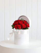 The Wild flower Juliet arrangement featuring one dozen premium red roses in a white hatbox with a white ribbon.