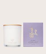 The Wild flower Living Light Black Iris scented candle in a white glass jar with a wooden lid and purple box.