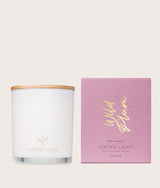 The Wild flower Living Light scented soy candle in a white glass jar with wooden lid and pink Wild Plum gift box.
