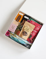 The Wild flower Luxury Treat Box featuring gourmet cookies, chocolates, nuts, and a candle, decorated with fresh flowers.