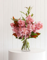 The Wild flower Cymbidium Orchid Stem bouquet featuring pink orchid blooms and seasonal foliage in a glass vase.
