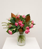The Wild flower Seasons Best Tulips bouquet featuring pink ruffled tulips and seasonal greenery in a ribbed glass vase
