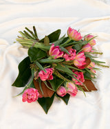 The Wild flower Seasons Best Tulips bouquet featuring pink ruffled blooms and dark green magnolia leaves.