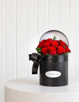 The Wild flower Juliet arrangement featuring a dozen premium red roses in a signature black hatbox with a black ribbon.
