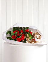 The Wild flower Romeo bouquet featuring premium red roses, lush greenery, and rose gold accents wrapped in white paper.