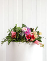 The Wild flower Florist Surprise bouquet featuring fresh seasonal pink, purple, and peach blooms with lush greenery.