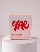 The Wild flower Yae Bio Collagen Face Mask box featuring red branding on a pale pink background on a white pedestal.